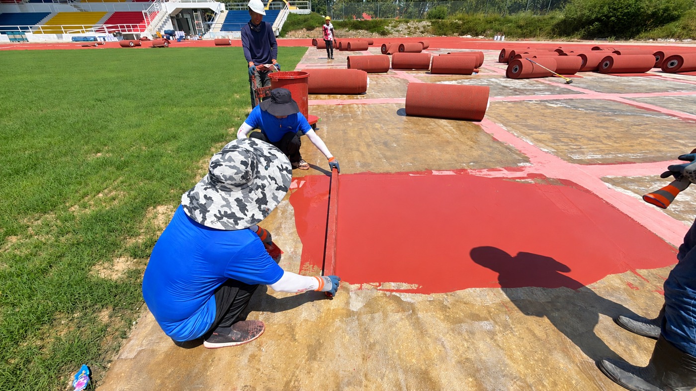 The installation team working at an adhesive-coated section of the track base.