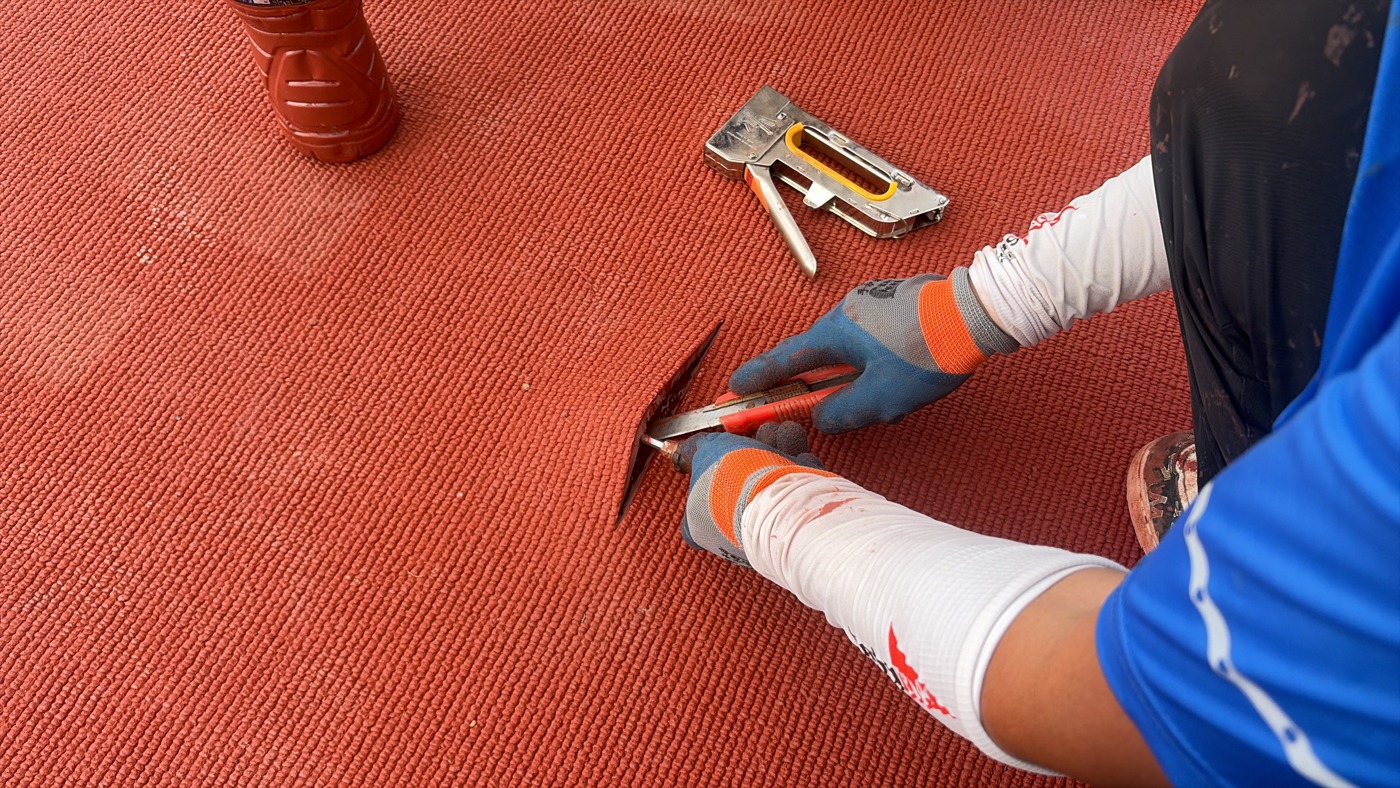Close-up of edge trimming during prefabricated rubber track installation.