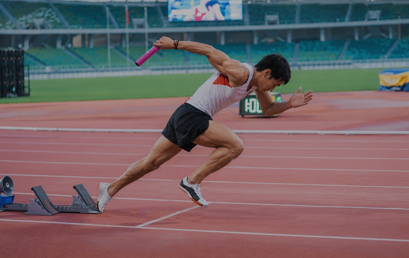 Sprinter accelerating from starting blocks on a red running track